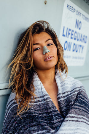 Woman wearing colorful reef safe Nöz spf sunscreen on her face